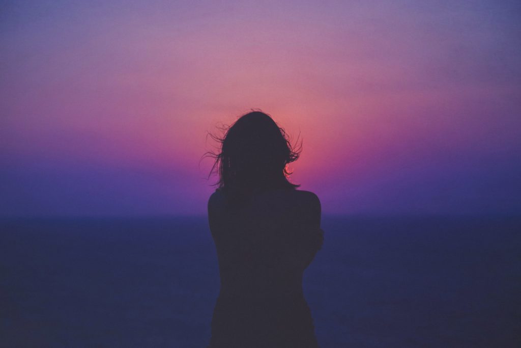 silhouette of a woman with pink and purple sky